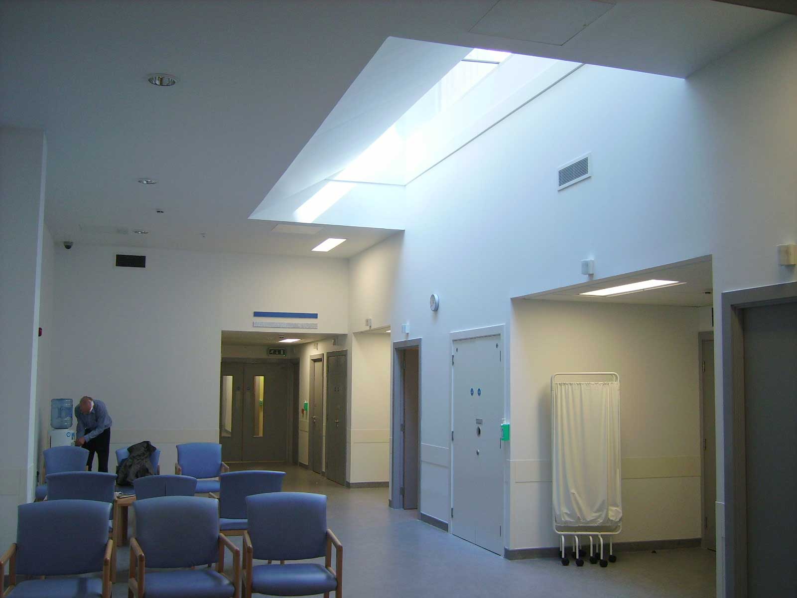A waiting area in a hospital setting with light coming in from a roof light