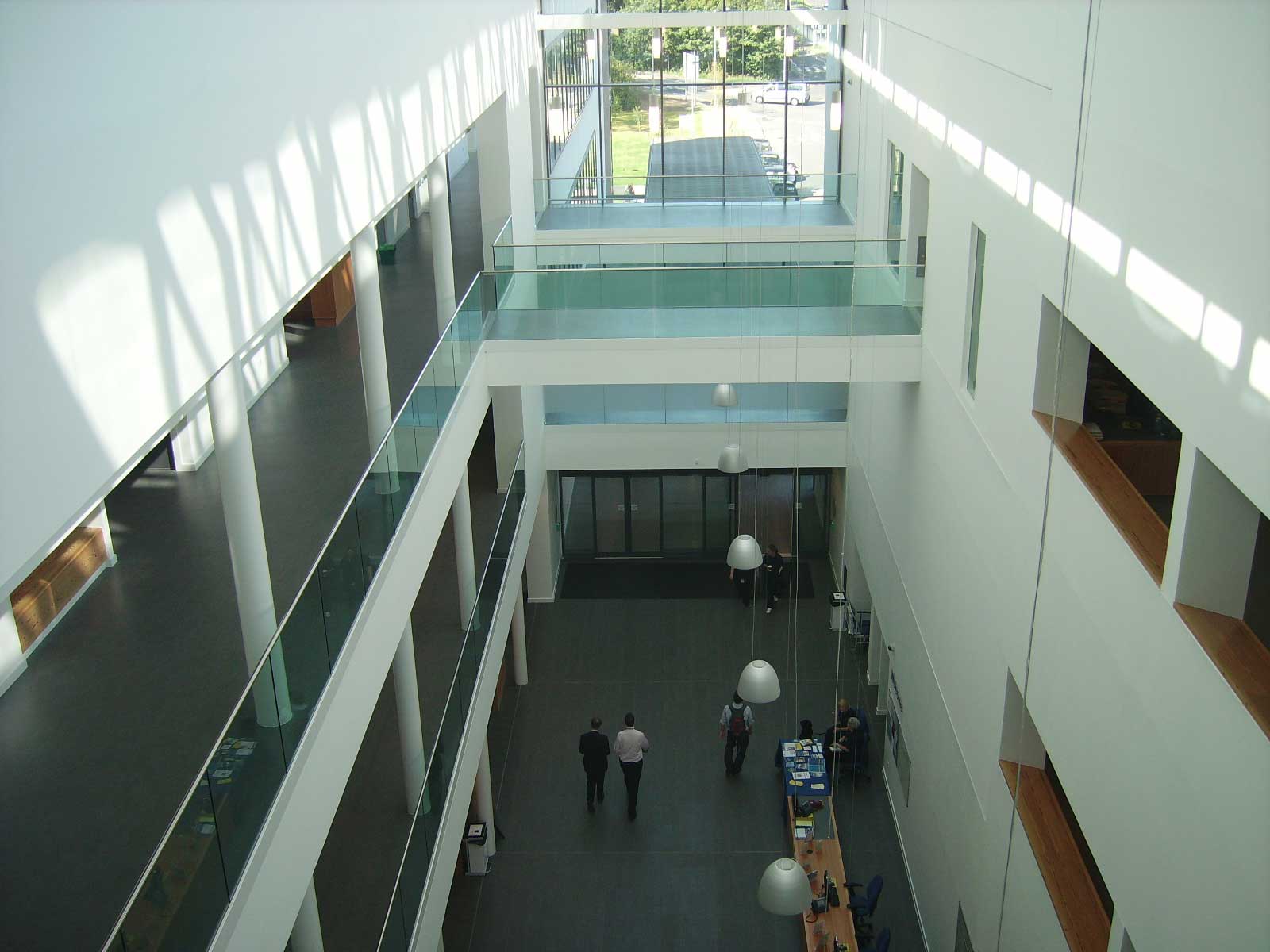 A view into an open atrium like reception with staircases and light fixtures hanging into the space