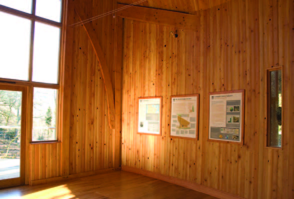 An interior photograph of a timber clad building with a number of photographs on the wall and a large wall of windows