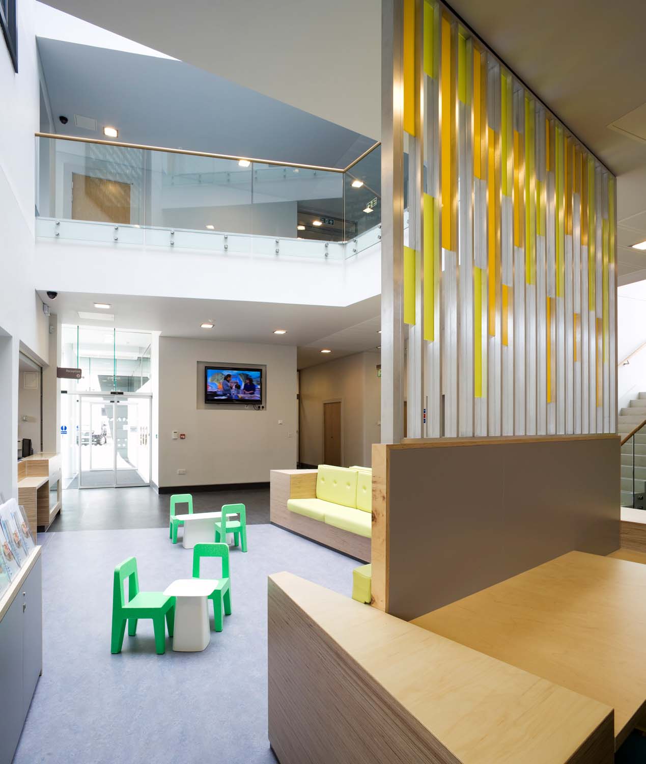  The ground floor reception area in the atrium space of West Centre Glasgow features yellow padded seating and kids' chairs and tables.