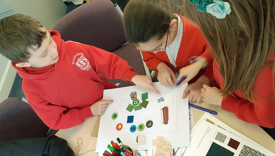 Pupils at Corstorphine Primary sat around a table and using the symbolic tools from the PDSA process.