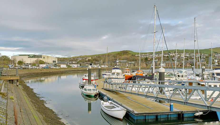 Campbeltown Harbour on a cloudy day. There are boats parked on the jetty.