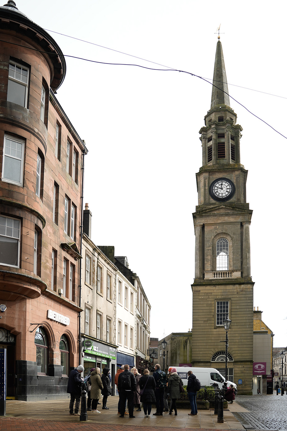 People standing below a landmark in Falkirk during a walking tour.