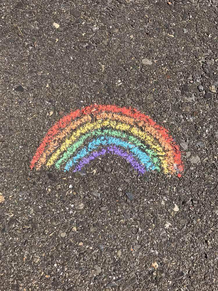 A close up of a chalk rainbow on a brown pavement surface