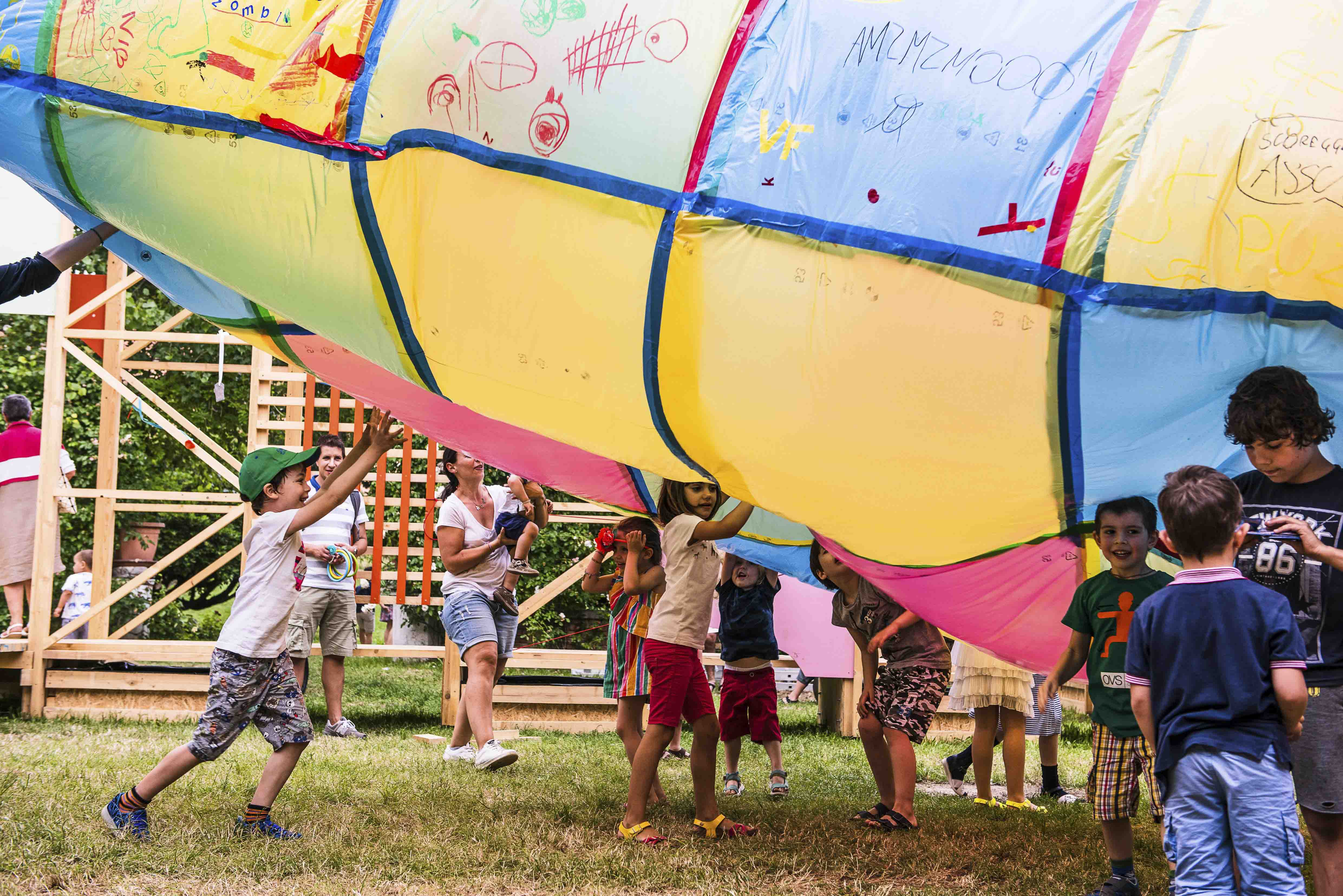 a group of young children play underneath a multi coloured inflatable object.