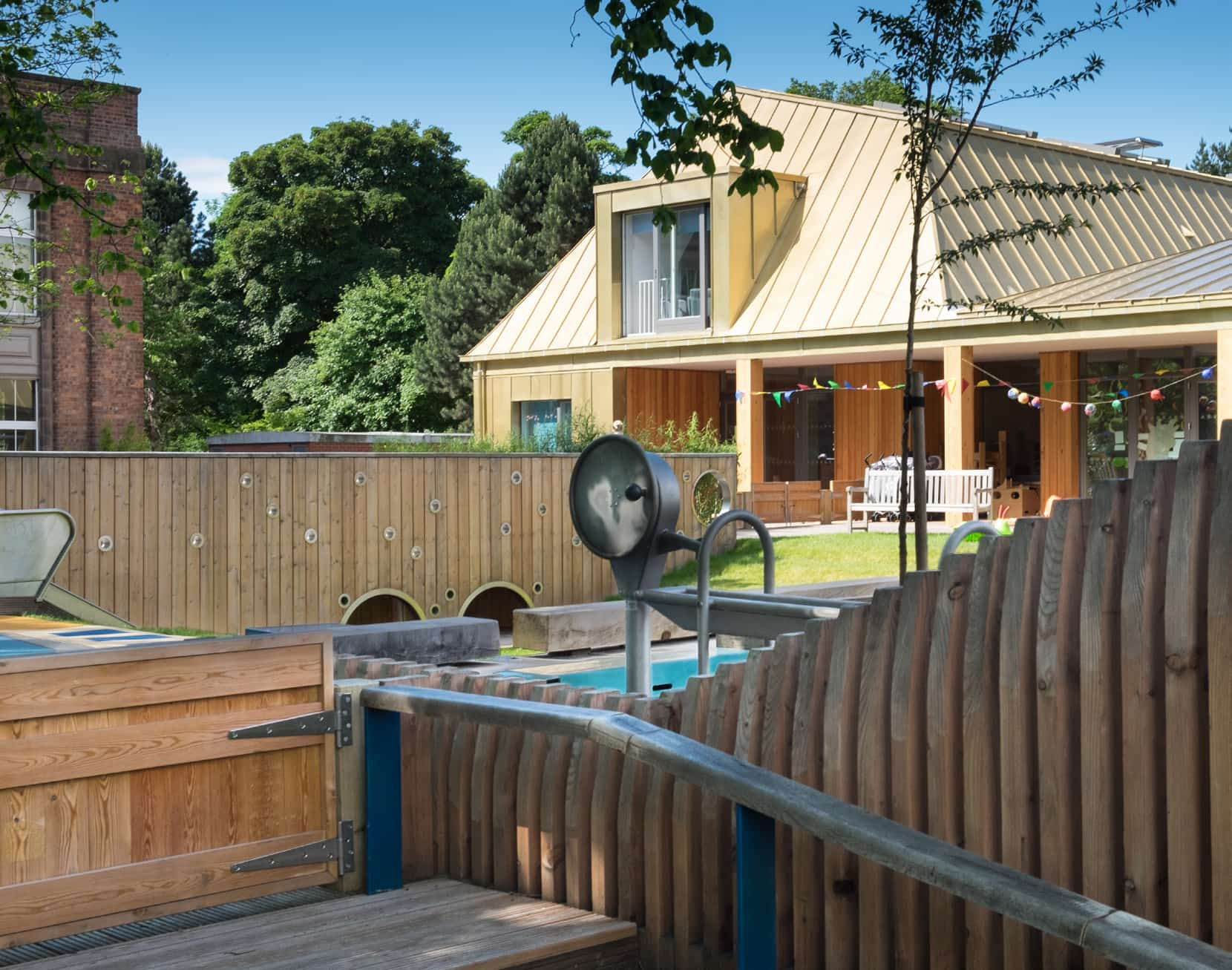 Arcadia nursery play garden with timber wall features, outdoor play equipment and the nursery building in the background.