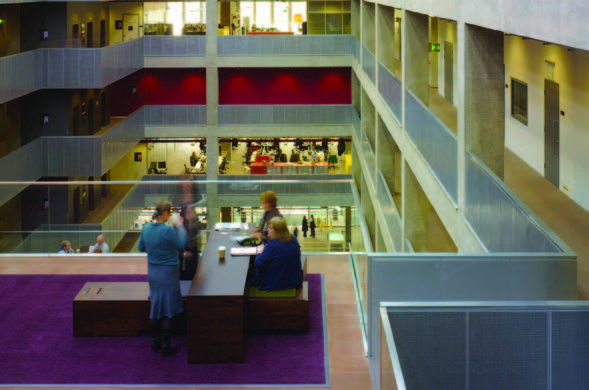 A view of a modern atrium with two people overlooking the balconies that surround the open space below