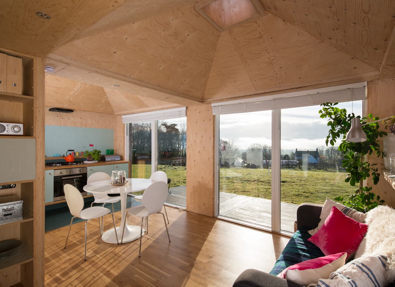 A kitchen and dining area with wide windows overlooking a rural landscape.