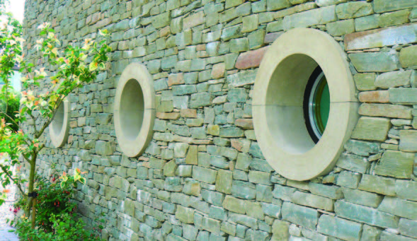 A stone wall with two round porthole type windows
