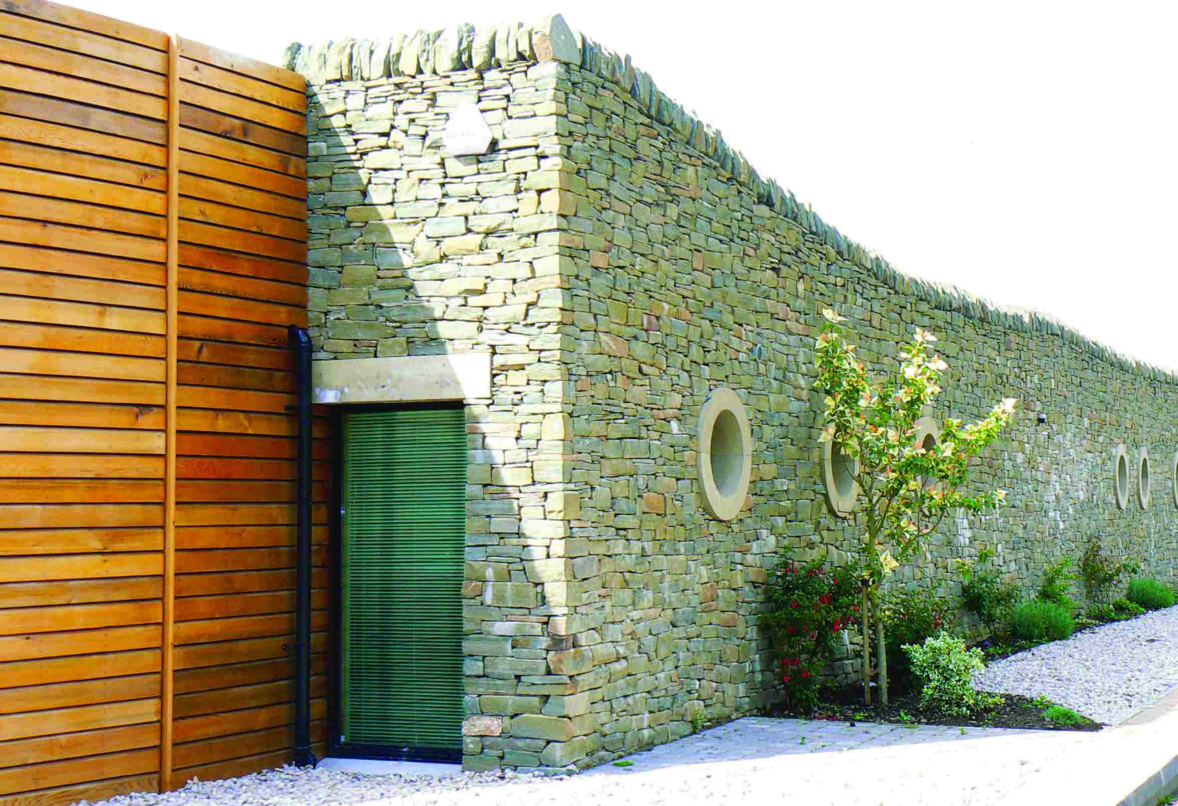 A long stone wall with a glass doors and portholes built into the wall. 