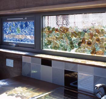 Sunlight streams in through a mosaic window made from recycled glass above a sink