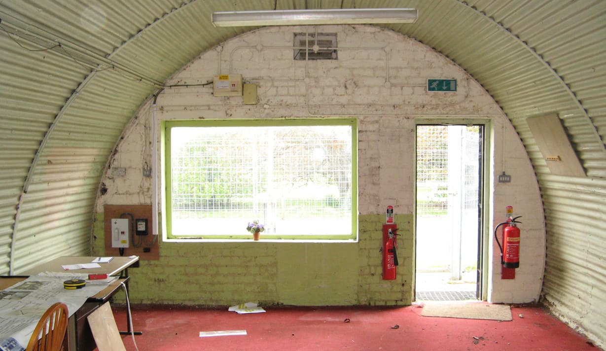 The interior of a semi circle shaped building. The interior walls are lime green in colour matched with red carpet flooring.