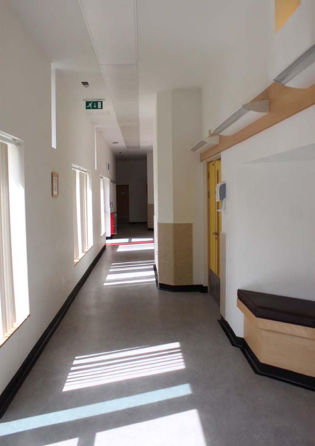A corridor in Elmview and Muirview Wards with white walls, cement flooring and black padded seating area.
