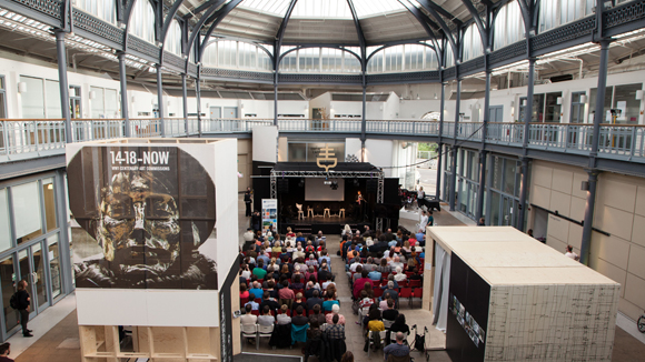 A view of an exhibition space and cafe with people sitting around tables surrounded by displays