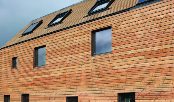 The horizontal timber cladding at the Flower House contains flower details cut into the wood and black framed windows and skylights.