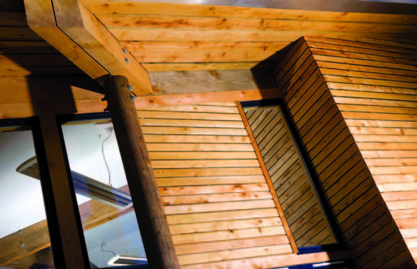 A close up of the European larch heartwood exterior cladding underneath the roof of the building. The wood is fitted horizontally onto the walls.