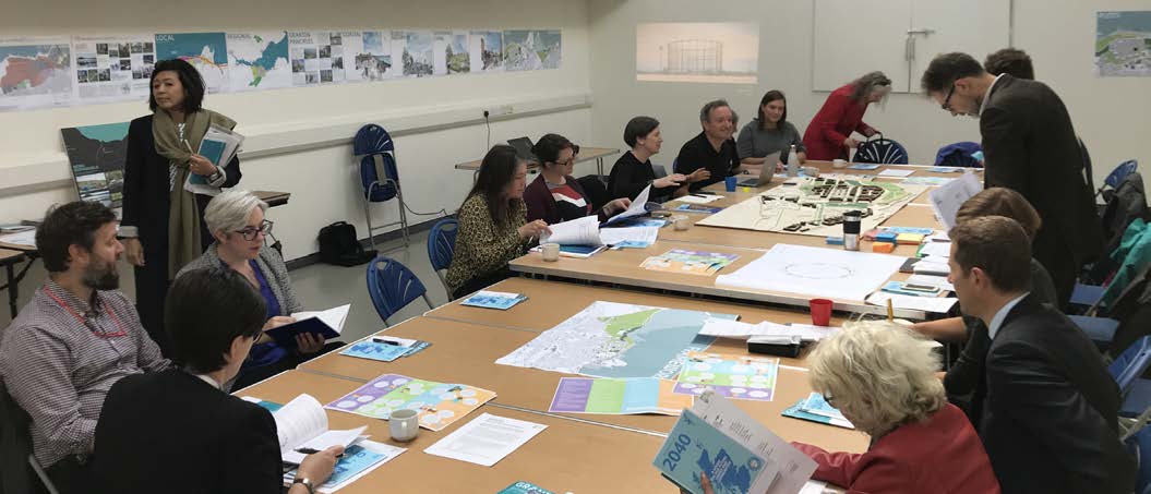 About 15 people sitting and talking around a long table at a workshop.