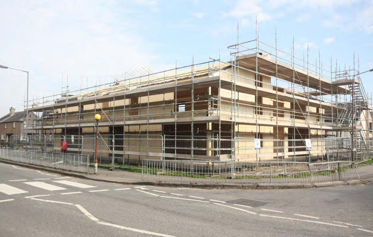 A photograph of a building during construction on a street corner - you can see the timber structure behind scaffolding. 