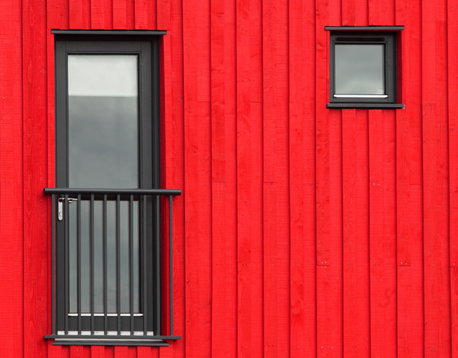 A glass door and a square window. Both have a black frame and are surrounded by vertical bright red horizontal panels.