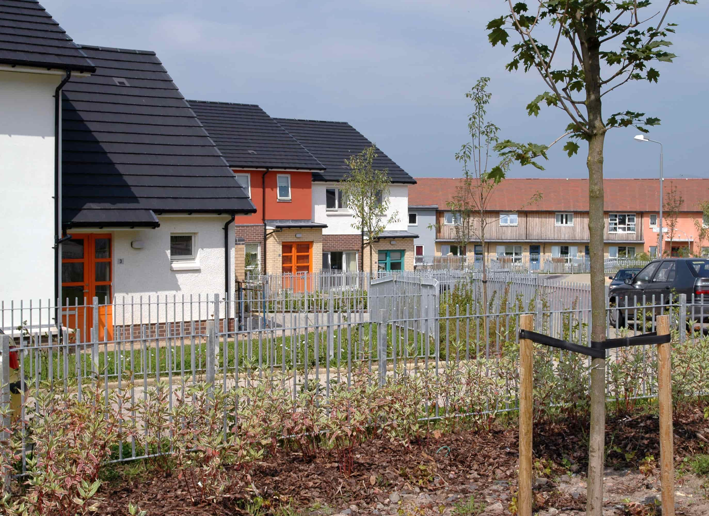 A group of houses with colourful front doors and black roofs.