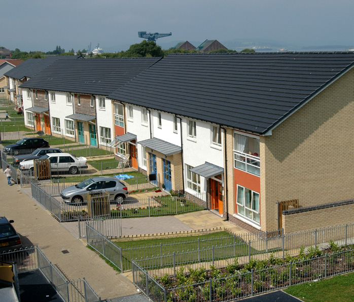 A row of two-storey houses with front gardens overlooking a quiet street.