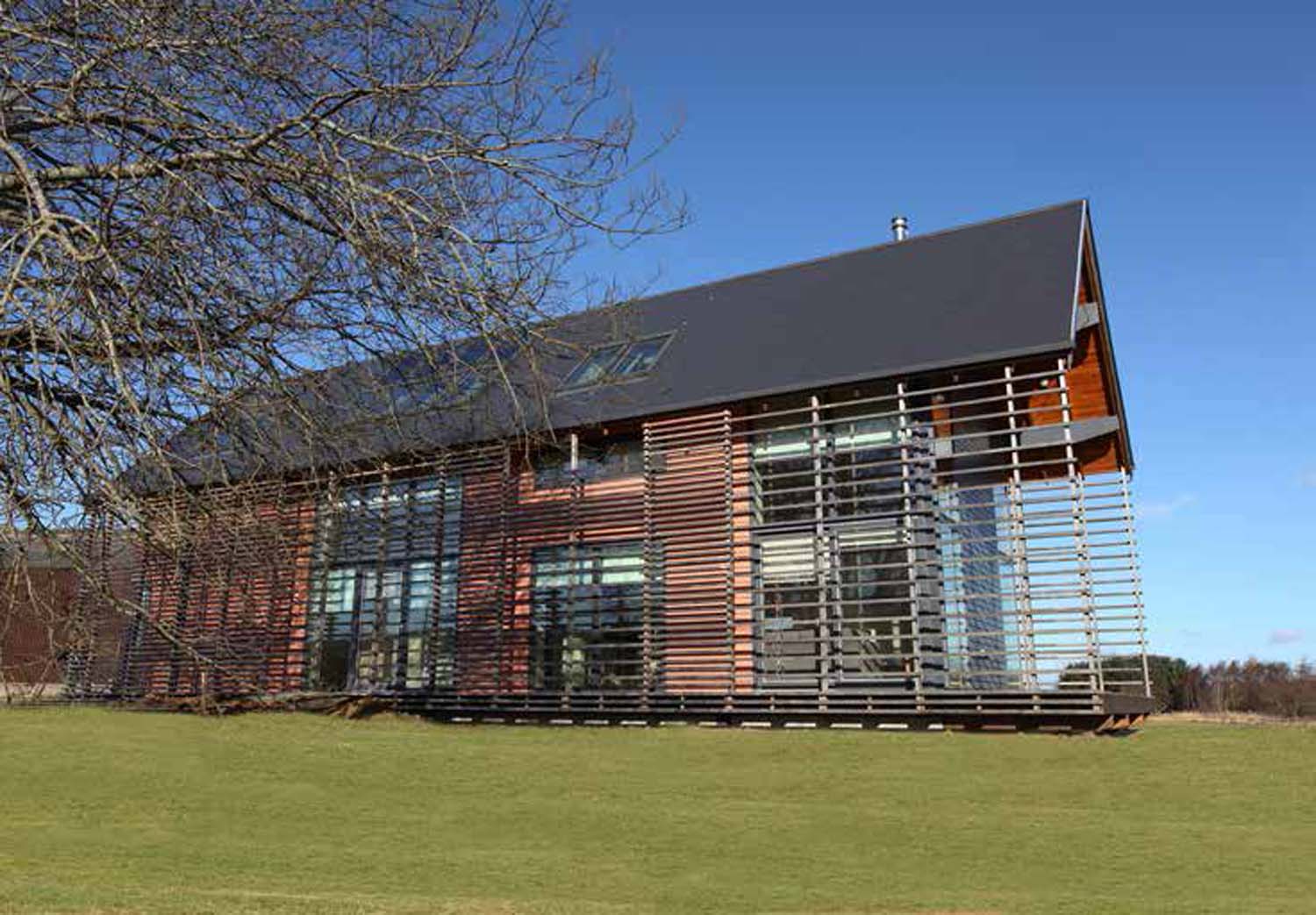 A photograph of  large timber building sitting on a small hill in an open landscape