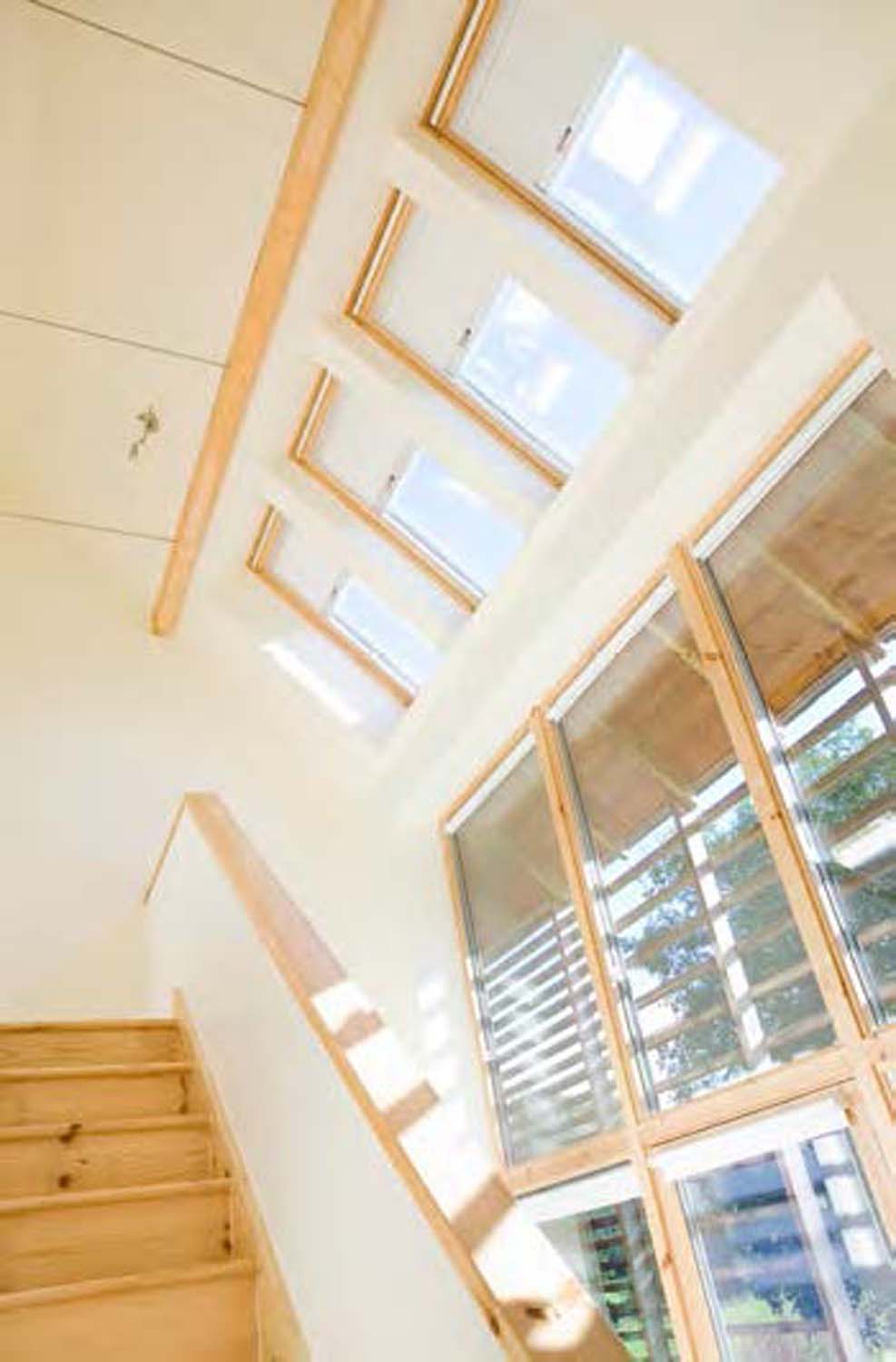 A photograph of a light filled double height interior showing sunlight streaming in through the windows