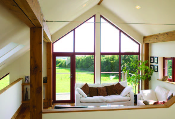 An interior living area on the first floor of a house. The space overlooks the garden, seen through floor to ceiling windows and a glass door.