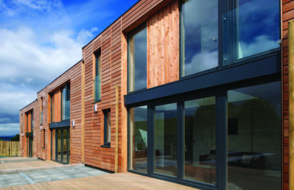 A row of houses clad in Scottish Larch and with large black gates and window frames
