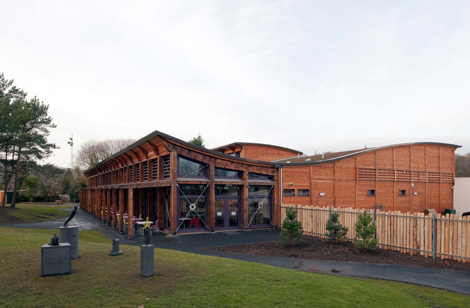 An outdoor view of the Robert Burns Birthplace Museum cafe. The building has a curved roof covered in grass with timber cladding around it.