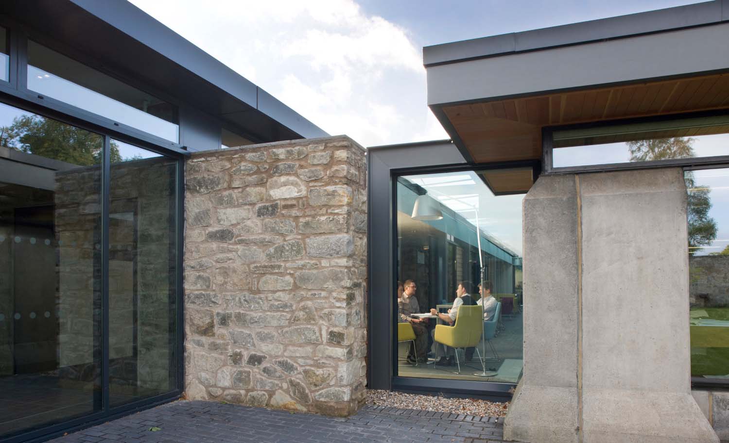 Employees have a meeting at the junction of Scotstoun house. The view is taken from the outside and into the building.