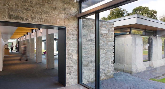 A black doorless frame built into a stone wall leads to the interior junction at Scotsoun House. The stone wall continues to the outdoors.