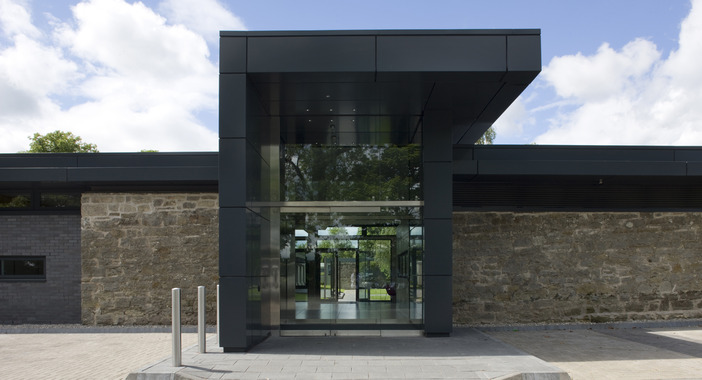 A large black entrance canopy covers the double glass door entrance to the Scotstoun House office.