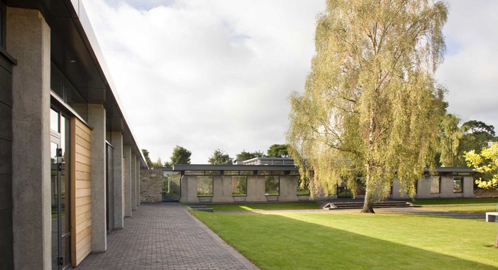 The courtyard at Scotstoun House has green grass and a large tree in its centre.  