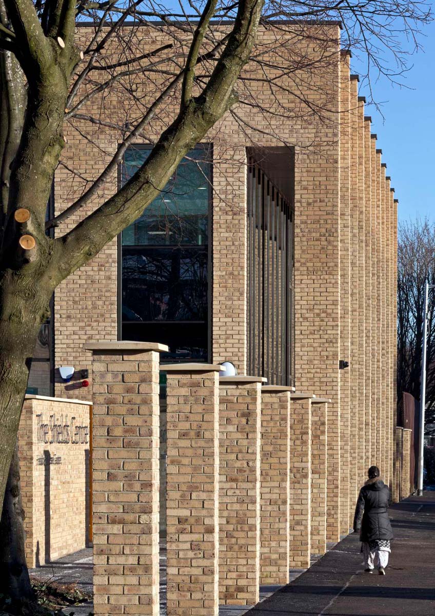 An exterior photograph of the entrance to a health centre housed in a light coloured brick building with a colonnade of brick pillars 