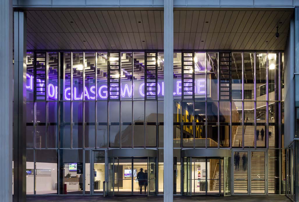 A City of Glasgow College sign in neon purple next to the modern campus theatre. A view from the outside looking into a large window.