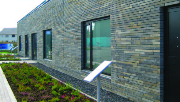 A closer look at an exterior stone cladding on a building. The stones vary in grey colours and are thin with variable lengths.