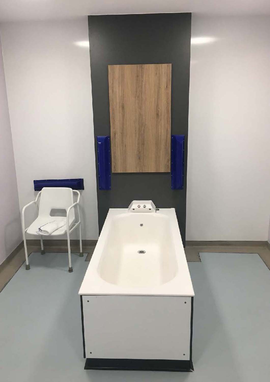 A bathroom space featuring a bathtub and a chair with a towel next to it.