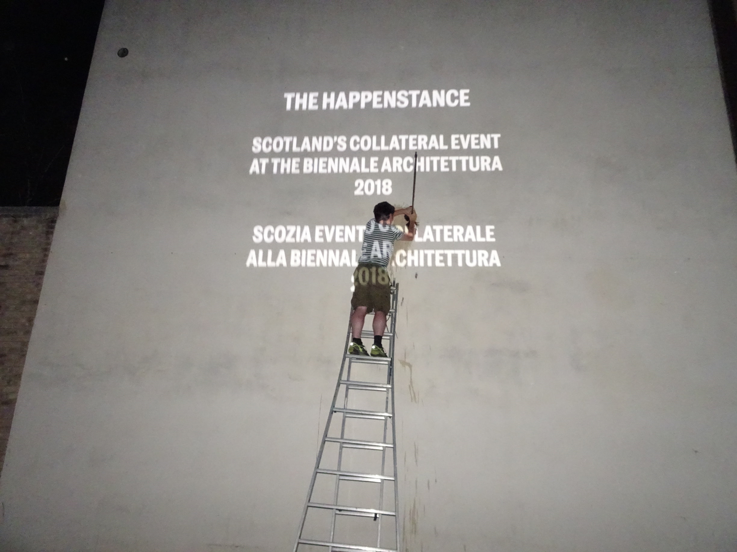 The Happenstance curator Peter McCaughey is up a ladder cleaning the project’s vast screening wall.