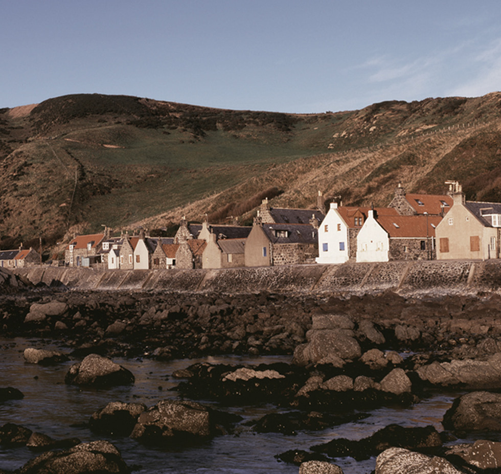 A row of traditional stone built houses in a rural setting by the sea. 