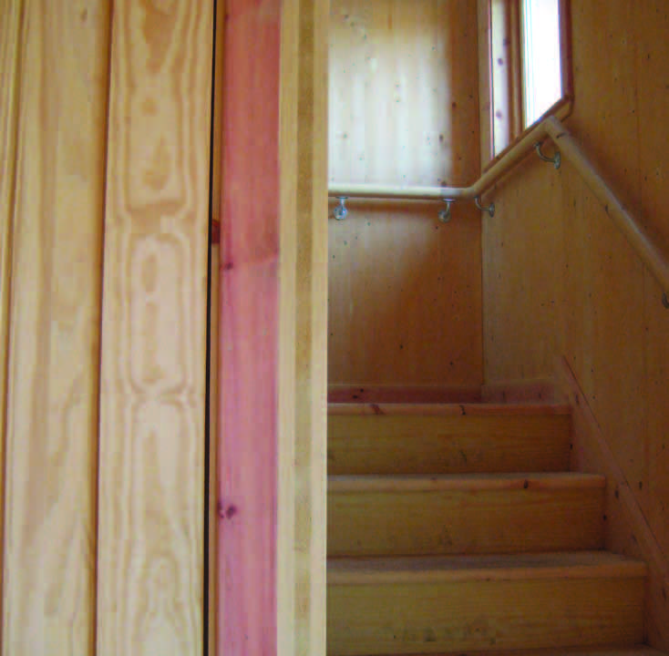 The unpainted interior wall of the stairwell at the Timber House with a window shows the cross-laminated timber panels.