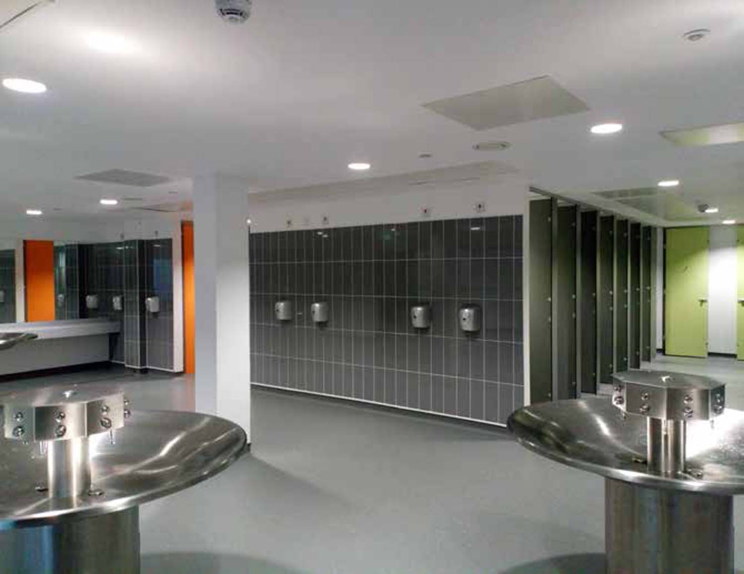 School toilets with orange and green cubicle doors.
