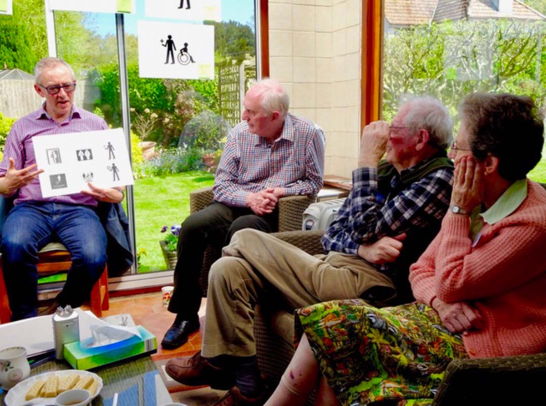 A person showing accessible symbols to a group of elderly.