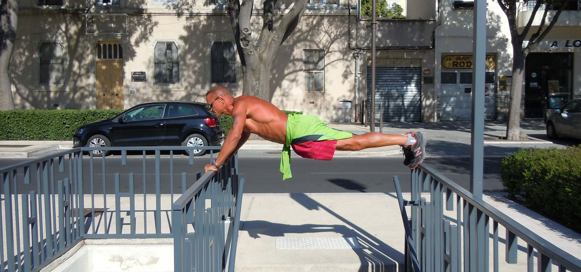 A man balancing himself on top of two metal railings is doing push ups.
