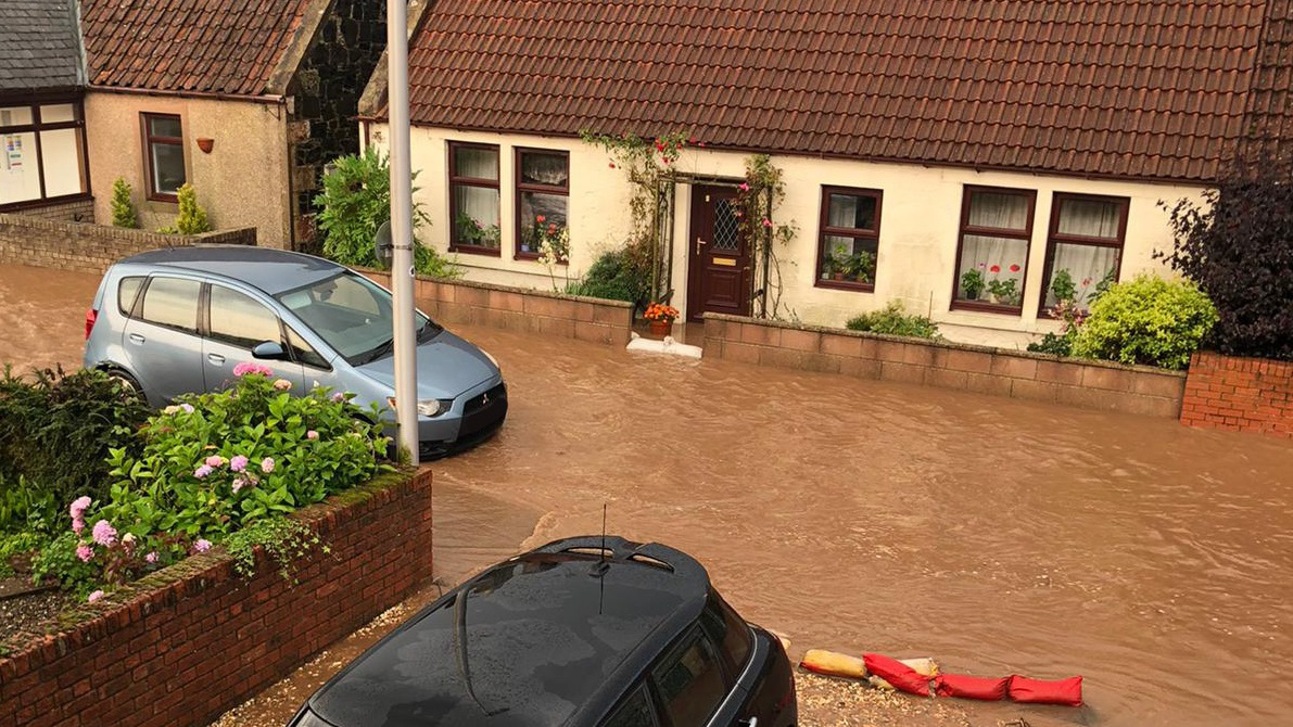 Floods in Fife after severe thunderstorms in August 2020. A car is attempting to drive through the water in a housing area.