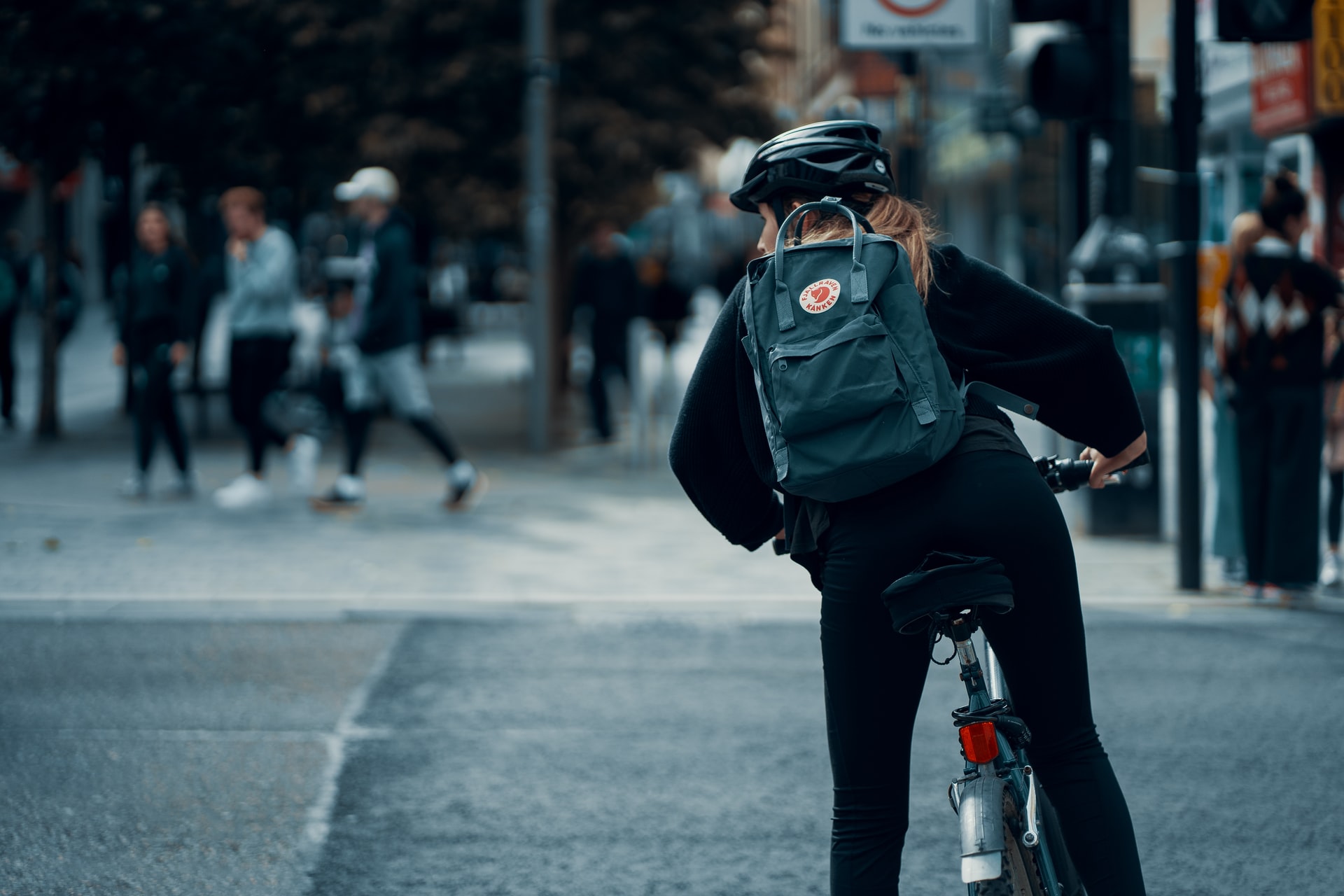 A woman on a bike on Sauchiehall Street in Glasgow. She is wearing a helmet and a backpack.
