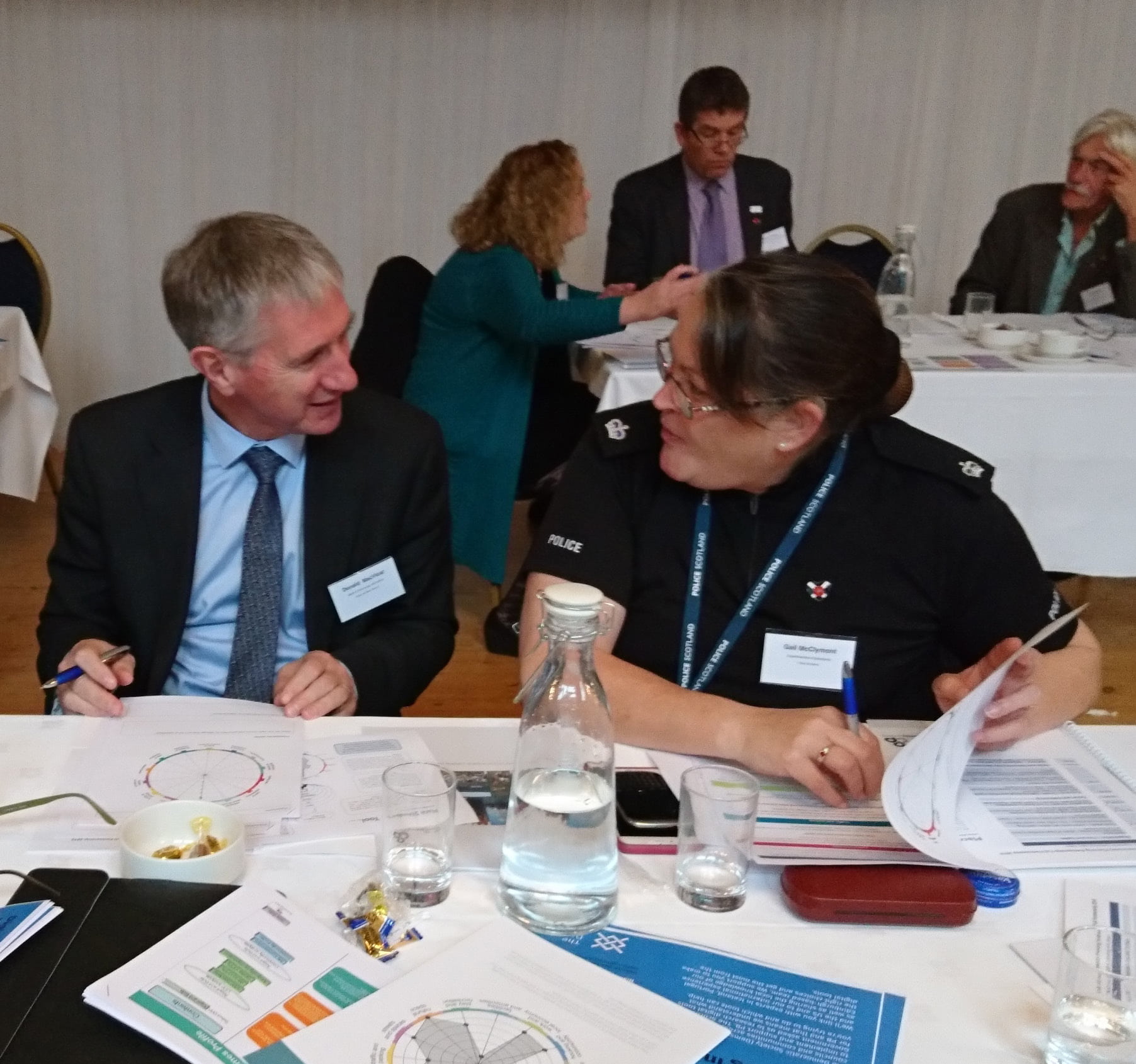 A police officer and a professional talking at a table during a Place Standard workshop in Argyll and Bute.
