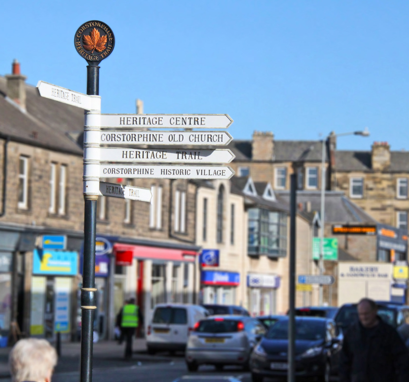 A street sign on Corstorphine's High Street with directions for Corstorphine Old Church, Heritage Centre, Heritage Trail and Corstorphine Historic Village.