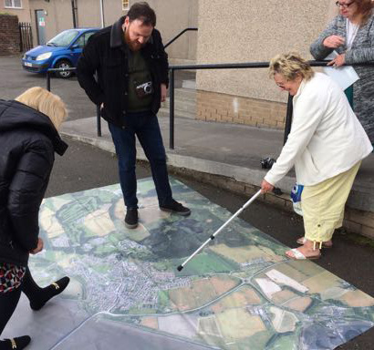 A woman points at an area on an aerial map on the floor during a Place Standard event in Kincardine.