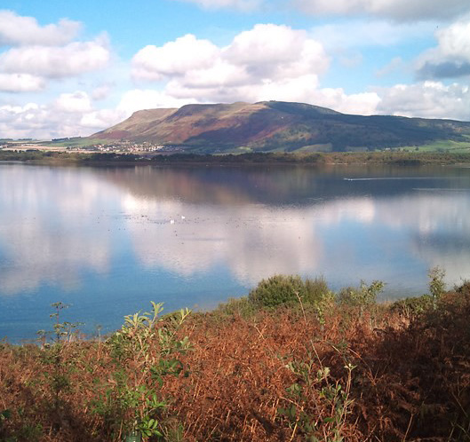 A loch in Portmoak Parish on a sunny day with mountains in the background.